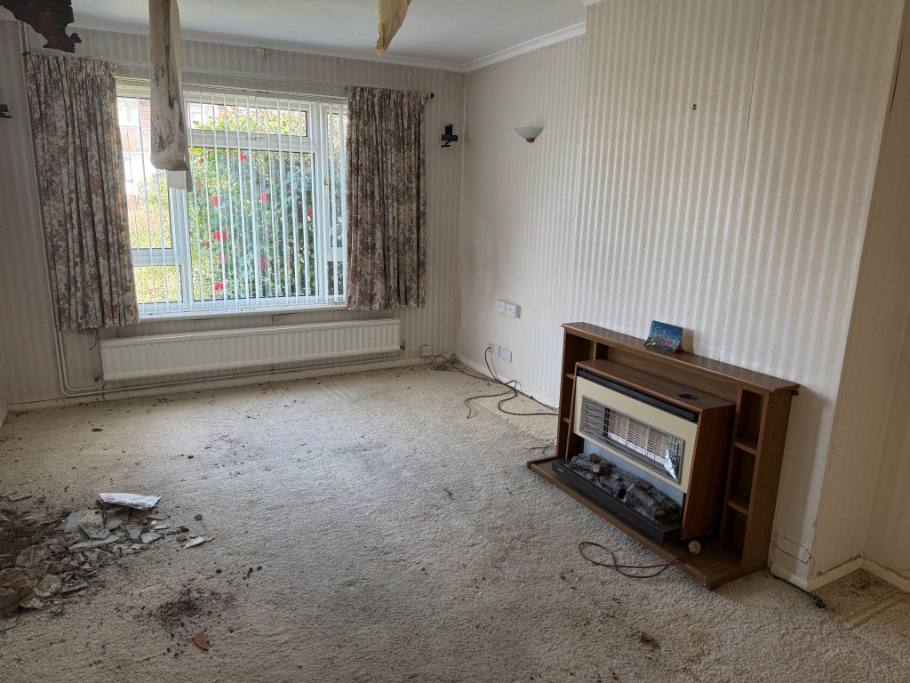 Lot: 128 - BUNGALOW WITH GARAGE AND GARDENS IN NEED OF MODERNISATION - Living room with gas fire and window to front